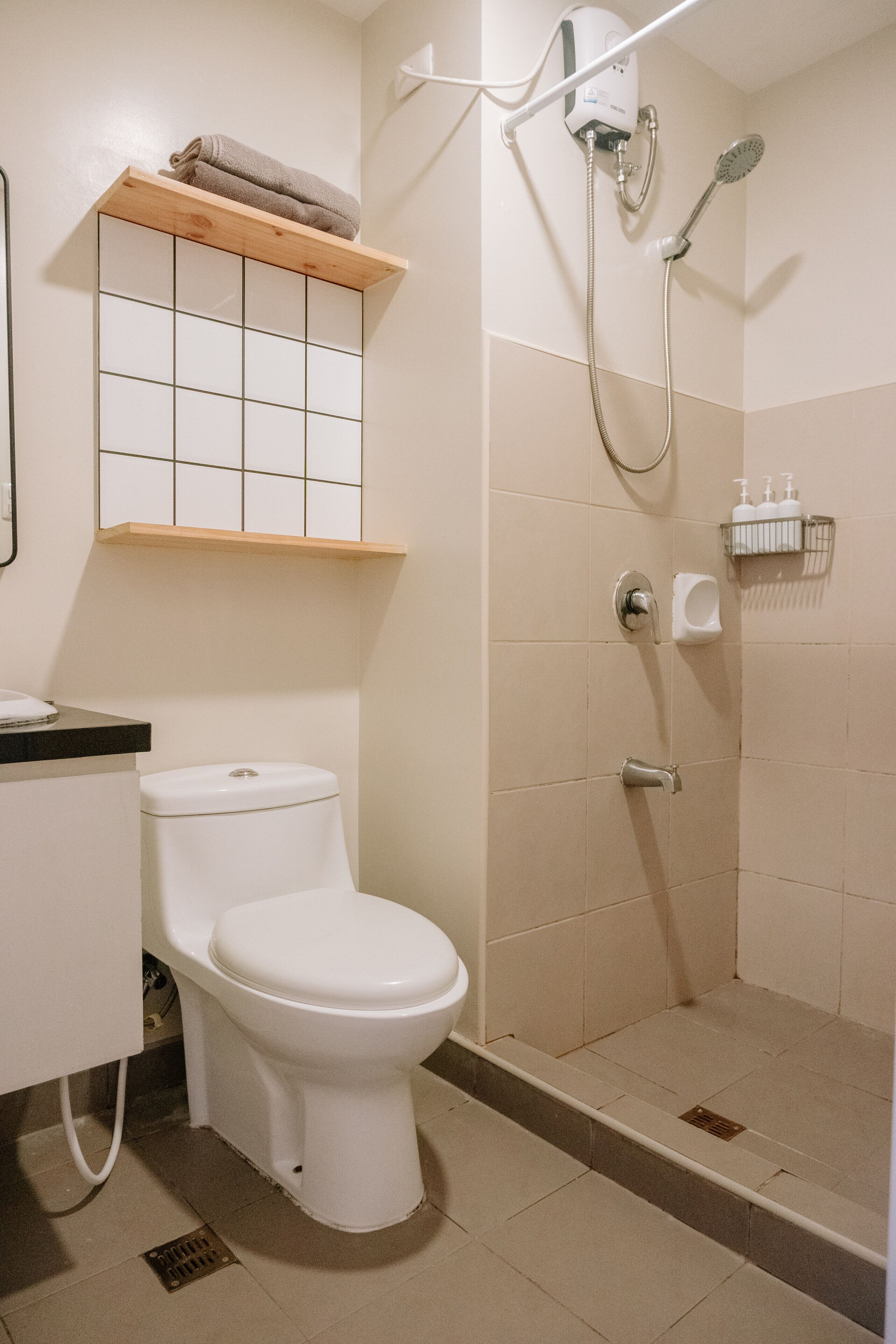 Een badkamer met toilet, douche en een plank met toiletartikelen.