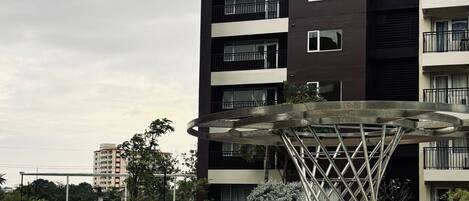 A modern apartment building with a swimming pool and a unique metal sculpture.