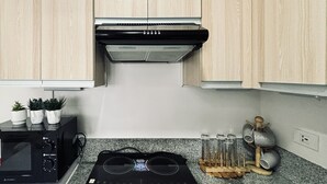 A kitchen with wooden cabinets, a black range hood, a microwave, and a stove. - Barkada Getaway Near Esplanade (Iloilo)