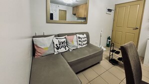 A living room with a grey sofa, two cushions with motivational text, a large mirror, a door, and a shoe rack. - Barkada Getaway Near Esplanade (Iloilo)