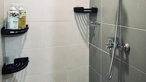A bathroom with a shower, a black towel rack, and two soap dispensers on a shelf. - Your Peaceful Urban Escape (Iloilo)