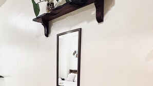 A small dining area with a wooden table and chairs, a mirror on the wall, and a shelf above the mirror. - Your Peaceful Urban Escape (Iloilo)