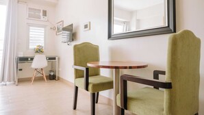 A room with a dining table, two chairs, a mirror, and a window with blinds. - Stunning Cityscape Hideout (Iloilo)