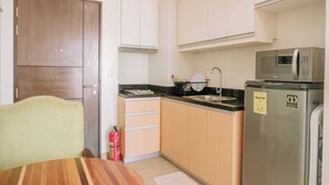 A compact kitchen with a microwave, sink, and wooden cabinets. - Stunning Cityscape Hideout (Iloilo)