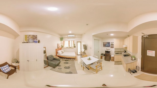 A spacious living area with a dining table, a sofa, and a kitchen area with a refrigerator and sink. - Tropical Bliss in the Metro (Iloilo)