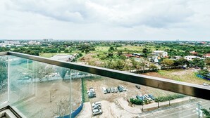 A high-rise building with a view of a parking lot and surrounding greenery. - Best Family Suite Experience (Iloilo)