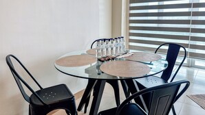 A round glass table with black chairs, water bottles, and woven placemats. - Best Family Suite Experience (Iloilo)