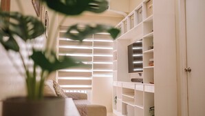 A living room with a sofa, a potted plant, and a white shelving unit with storage. - Playful & Charming City Loft (Iloilo)