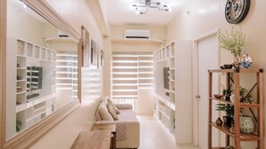 A well-lit hallway with built-in shelving, a bench, and a sofa. - Playful & Charming City Loft (Iloilo)