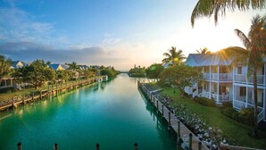 A waterway with docked boats, a wooden walkway, and beachfront villas. - Sunny Stay | Reef Snorkeling. Two Bedroom Private Villa (Duck Key)