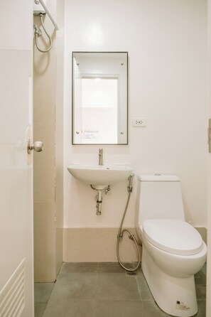 A small, clean bathroom with a white sink, toilet, and shower. - Tranquility in the City (Iloilo)