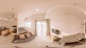 A modern living room with a curved sofa, a flat-screen TV, and a dining area with a marble table. - Tranquility in the City (Iloilo)
