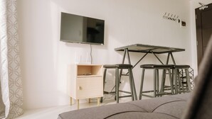 A room with a bed, a desk with two chairs, a TV, and a coat rack. - Tranquility in the City (Iloilo)