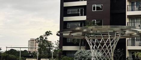 A modern apartment building with a swimming pool and a unique metal sculpture.