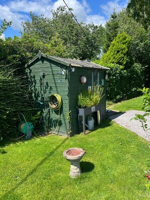 A small green shed with a hose and a birdbath in front. - Cosy Grasmere Static Caravan (Natland)