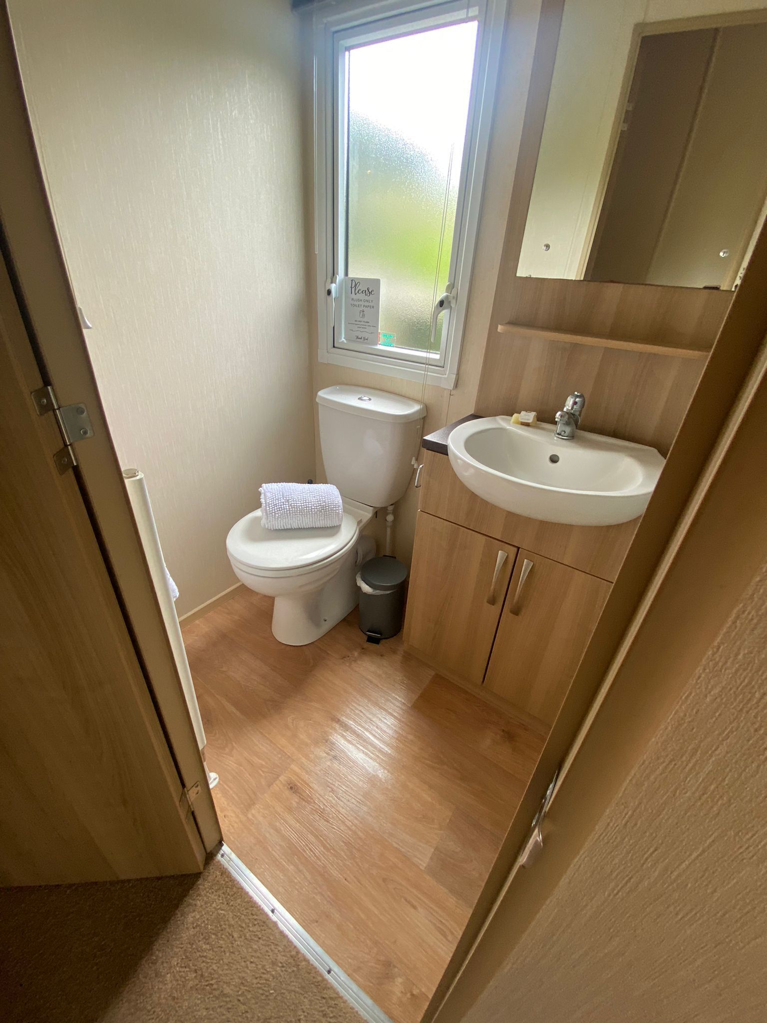 A compact bathroom with a toilet, sink, and a small trash bin.