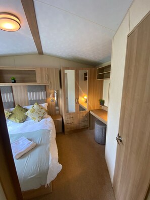A compact bedroom with a bed, bedside tables, a mirror, and a wardrobe. - Cosy Rydal Static Caravan (Natland)