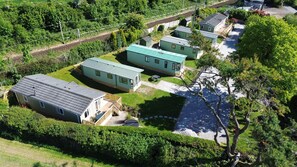 A row of mobile homes with a paved driveway and a small pool area. - Cosy Rydal Static Caravan (Natland)
