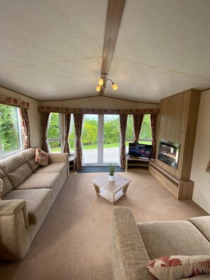 A cozy living room with a sofa set, a coffee table, and a flat-screen TV. - Cosy Rydal Static Caravan (Natland)