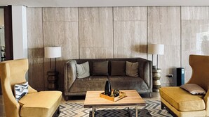 Ein modernes Wohnzimmer mit einer Couch, zwei Sesseln, einem Couchtisch und einem gemusterten Teppich.