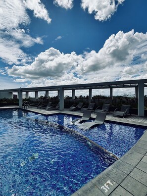 A swimming pool with lounge chairs and a pergola structure. - A Budget-friendly Retreat (Iloilo)