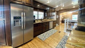 Una cocina moderna con electrodomésticos de acero inoxidable, armarios de madera oscura y una alfombra estampada.