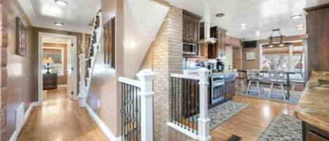 A spacious kitchen with a central island, wooden flooring, and a staircase leading to an upper level.