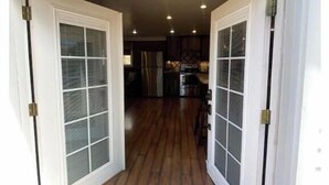 A view through a glass door into a kitchen with wooden flooring and a central island.