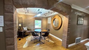 A dining area with a round table, chairs, and a stone wall.