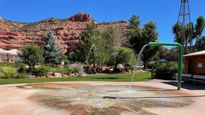 A water feature with a fountain in a park area, surrounded by greenery and a mountain backdrop. - Serene downtown Kanab hub for Zion, Bryce, Lake Powell, & Grand Canyon with yard (Kanab)