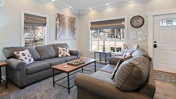 A living room with a grey sofa, a coffee table, and a ceiling fan. - Serene downtown Kanab hub for Zion, Bryce, Lake Powell, & Grand Canyon with yard (Kanab)