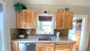 A kitchen with wooden cabinets, a built-in dishwasher, and a stone backsplash. - Serene downtown Kanab hub for Zion, Bryce, Lake Powell, & Grand Canyon with yard (Kanab)