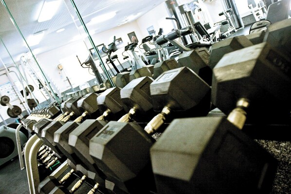 A gym with rows of dumbbells and exercise equipment.