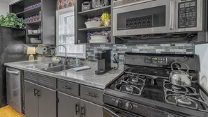 A modern kitchen with stainless steel appliances, a gas stove, and a microwave. - Cute 2-bedroom bungalow in downtown Raleigh (Raleigh)