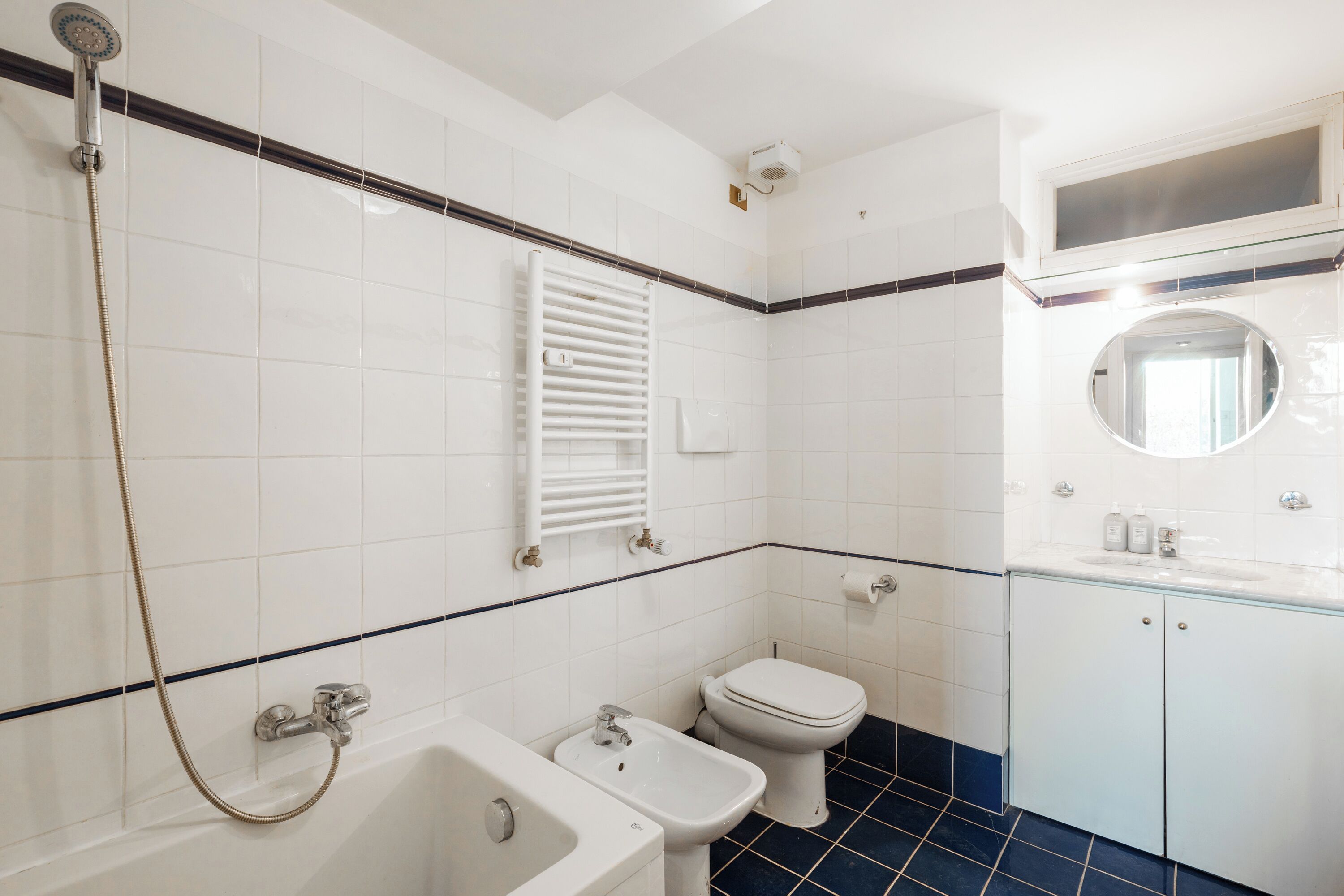 A bathroom with a bathtub, a bidet, a toilet, and a mirror.