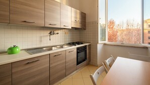 Une cuisine moderne avec des meubles en bois, un évier en acier inoxydable et une fenêtre donnant sur les arbres.