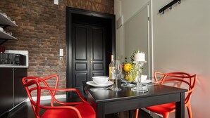 Une cuisine moderne avec un mur en briques, des meubles de couleur noire et des chaises rouges.