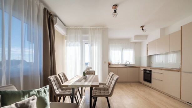 Una cocina moderna con comedor, que incluye una mesa de madera, sillas y vistas a la ciudad.