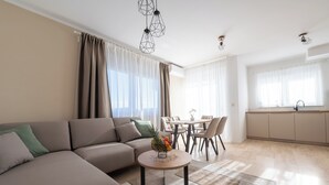 Una sala moderna con un sofá, una mesa redonda de centro y una zona de comedor.