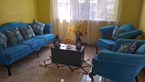Ein Wohnzimmer mit zwei blauen Sofas, einem schwarzen Couchtisch und einer Vase mit gelben Blumen.