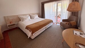 Habitación de hotel con cama, una silla, escritorio y ventana con cortinas.