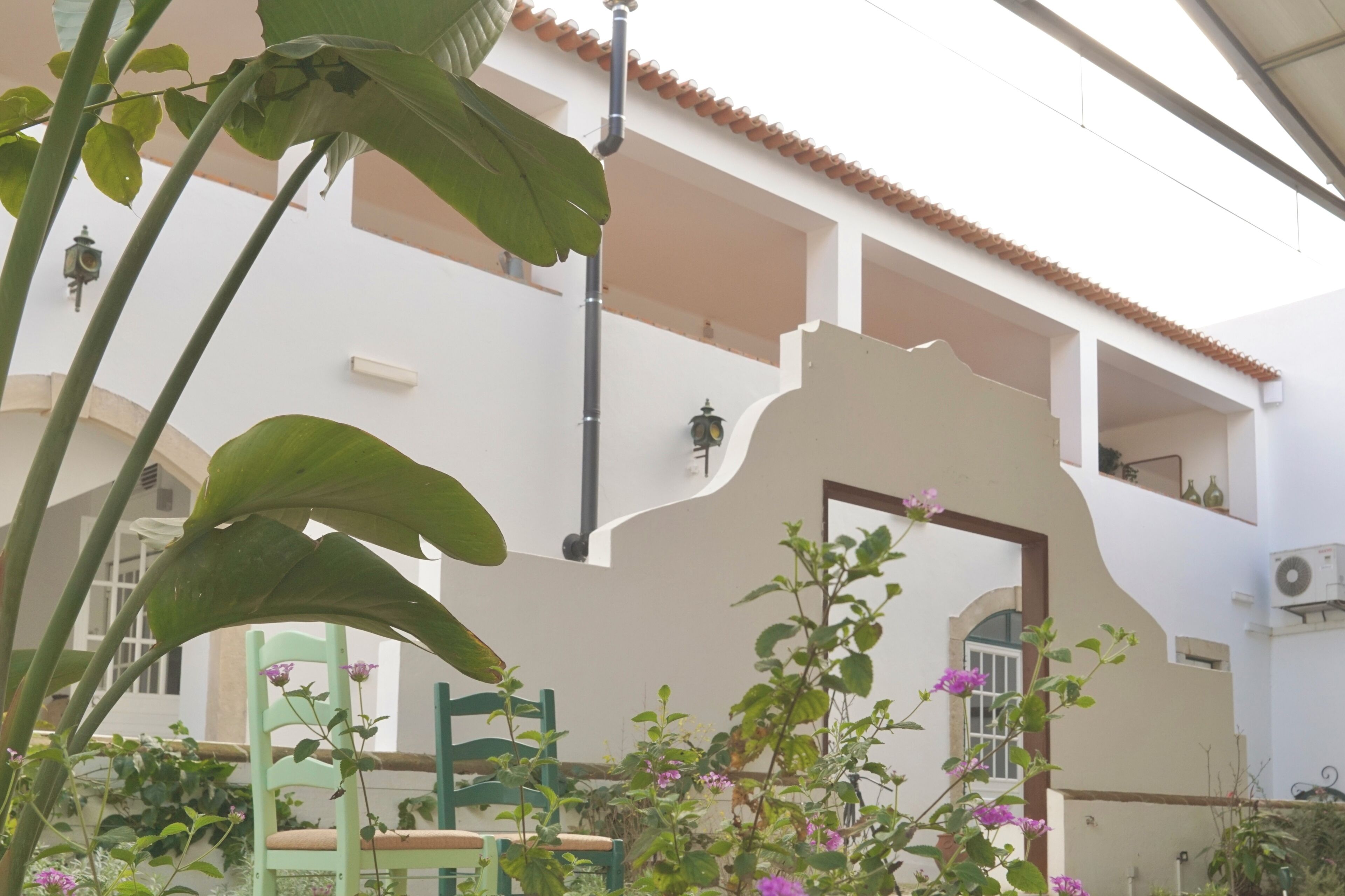Ein Gebäude mit weißer Fassade, Terrakotta-Dachziegeln und einem Balkon mit Geländer.