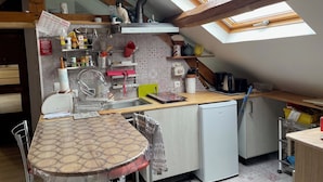 Una cocina compacta con tragaluz, un lavamanos, un refrigerador pequeño y una zona de comedor con mesa y sillas.