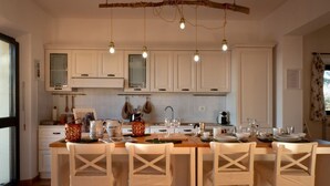 Een moderne keuken met witte kastjes, een houten eiland met barstoelen, hanglampen en een rustieke plafonddecoratie.