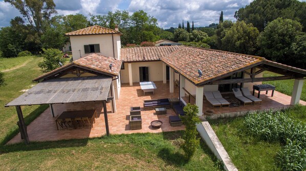 A villa with a tiled roof, outdoor seating area, and a covered patio.