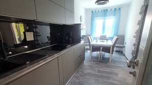 Et moderne køkken med grå skabe, en sort komfur og et spiseområde med et bord og stole.