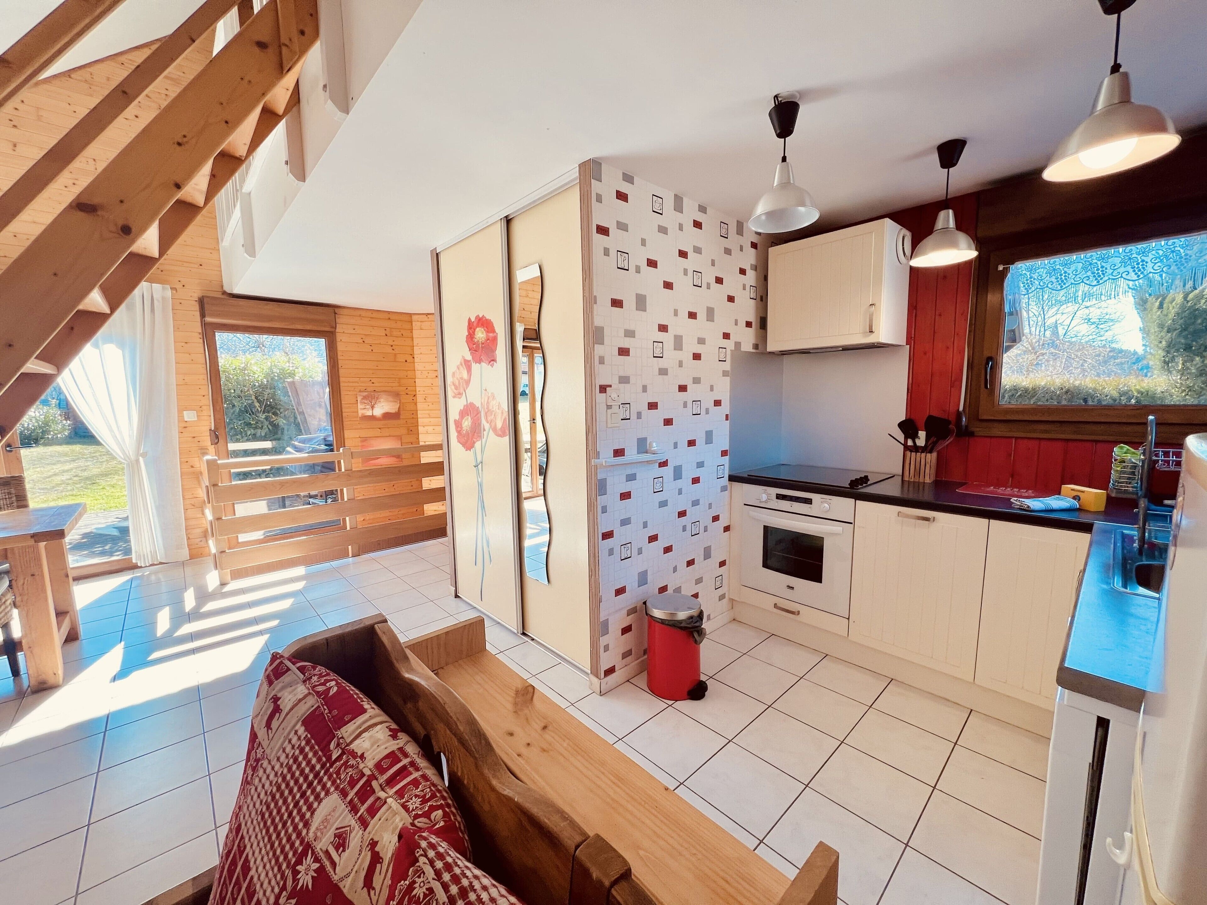 A modern kitchen with wooden accents, a dining area with a bench, and a view of the outdoors.