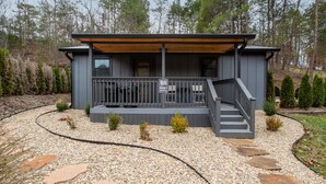 Eine moderne Hütte mit überdachter Veranda, Steinstufen und einem Schild, das Whiskey-Steine anzeigt.