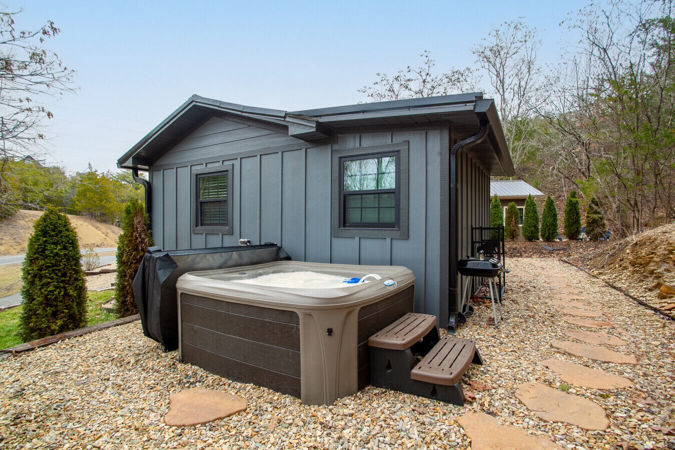 Una casa moderna con jacuzzi, un patio cubierto y un sendero de piedra.