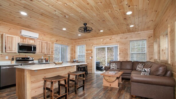A wooden cabin interior with a kitchen, dining area, and living room.